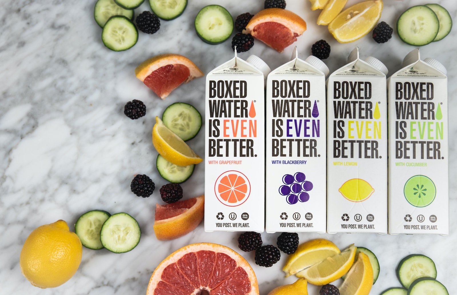 three boxes of boxed water are surrounded by sliced fruit